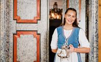 Ei smilande vertinne i tradisjonell norsk bunad ønskjer velkomen til Utne Hotel.
