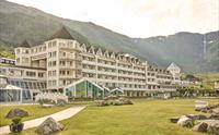 Hotel Ullensvang ligg vakkert til ved Hardangerfjorden, omkransa av grøne hageområde og majestetiske fjell.