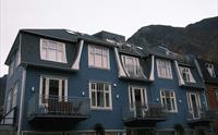 Den blå fasaden til Blue House Odda med fjellandskap i bakgrunnen, sentralt plassert i Odda.