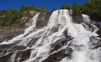 Nærbilete av Furubergsfossen – Vasskrafta til Furubergsfossen i fokus, med eit vakkert regnbogeskimmer i vatnet.