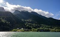 Hardangerfjorden badar i solskinn med majestetiske fjell i bakgrunnen.