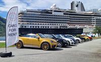 Et utvalg av VolksWagen boble leigebiler foran et cruiseskip.