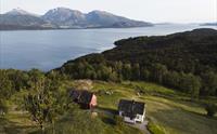 Dronebilde av Stigen Fjordlodge med fjord og fjell i Hardanger.