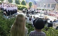 Choir singing on a small town square with crowds listening