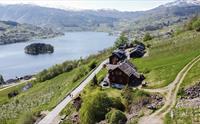 Dronefoto av Syse Gard, omkransa av frukthagar og fjordlandskap i Hardanger.