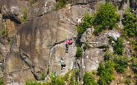 Tre personar klatrar via ferrata på loddrett bergvegg ved Valhall i Odda, sikra med hjelm og sele.