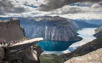 Spektakulær utsikt frå Trolltunga, eit av Noregs mest ikoniske fjellformasjonar, med blått vatn og dramatiske fjell i bakgrunnen.