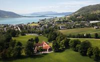 Dronebilete av Baroniet Rosendal Avlsgård og Fruehus – Storslått utsikt over det historiske gardsanlegget, omgitt av grøne marker og Hardangerfjorden i bakgrunnen.
