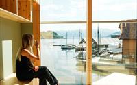Kvinne nyter kaffipausen med storslått utsikt over fjorden og trebåtane ved Hardanger Fartøyvernsenter.