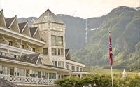 Det ikoniske tårnet på Hotel Ullensvang med fossefall i fjellsida som bakteppe.