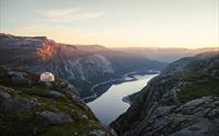 Glamping-dome ved Trolltunga med utsikt over Ringedalsvatnet i solnedgang – unik overnatting på Trolltunga Via Ferrata Sky Ladder.
