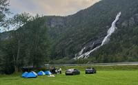 Telt og bilar på Hildal Camping med kveldssol over foss og fjell.