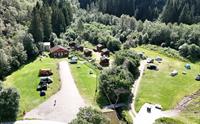 Flyfoto av Hildal Camping med hytter, teltplassar og grøne omgjevnader i Hardanger.