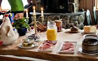 Frokostbord med stearinlys, en påskekylling, appelsinjuice og forskjellig pålegg.