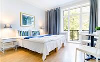 Eksklusivt hotellrom med dobbeltseng, balkong med utsikt mot Hardangerfjorden og stilrein innreiing.