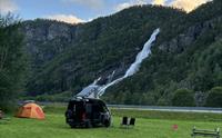 Campingvogn og telt på Hildal Camping med mektig foss i bakgrunnen.