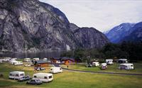 Utsikt over campingplassen med hytter, biler og campingvogner.