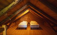 Loft med to enkeltsenger og trevegger i skråtak.
