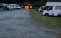 Kveldsstemning på Hildal Camping med lys frå servicebygget og bubilar parkert.
