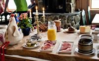 Frokostbord med en liten lysestake og blomster på Dyranut Fjellstova fjellstue.