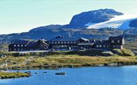 Finsehytta med et fjellvann i forgrunnen.