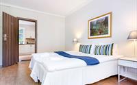 Komfortabelt hotellrom med dobbeltseng, klassisk innreiing og tilgang til eit kjøkken.