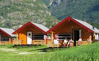Tre av hyttene på campingplassen, med folk som slapper av på en av terrassene.