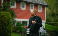 Olav Bleie frå Alde smakar på ost framfor eit tradisjonelt bygg i Hardanger.