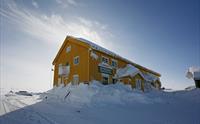Dyranut Turisthytta omgitt av snø og blå himmel.