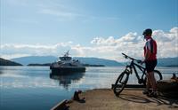 Syklist ventar på sightseeing-båten i Herand i Hardanger.