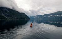 En enkelt kajakkpadler som padler på fjorden.