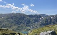 Utsikt over grønne fjellsider og et grønt vann.