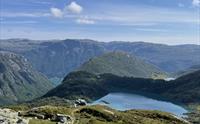 Utsikt over grønne fjellsider og et grønt vann.