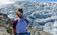 Kvinne sitter og ser utover Buerbreen, en del av Folgefonna.