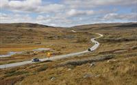 Noen biler kjører på Nasjonal Turistveg Hardangervidda om sommeren.