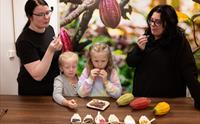 Two women and two small girls making and eating chocolate