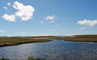 Fjellvannet ved Tinnhølen med blå himmel i bakgrunnen.