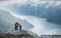 Tre turgåarar på toppen av Dronningstien med storslått utsikt over Sørfjorden og Folgefonna i bakgrunnen.