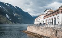 Bygningar frå Kraftmuseet i Hardanger med utsikt over fjorden, omgitt av vakre fjell og norsk natur.
