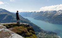 Turist ser ned på Sørfjorden frå fotturen Dronningstien i Hardanger.