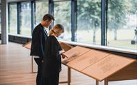 Besøkande studerar utstillingsmateriale i Kunsthuset Kabuso, med store vindauge ut mot naturen.