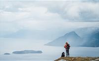 Kvinne og hund på tur i fjellet over Hardangerfjorden.