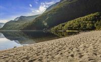 Sandstranda ved Eidfjordvatnet. Fjellene rundt innsjøen reflekteres perfekt i innsjøen.