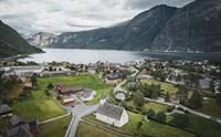 Et dronebilde av den gamle kirken med fjord og fjell i bakgrunnen.