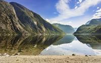 Sandstranda ved Eidfjordvatnet. Fjellene rundt innsjøen reflekteres perfekt i innsjøen.