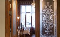 Stemningsfull inngang til restauranten på Thon Hotel Sandven, med klassiske utskjeringar og glasdetaljar.