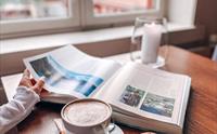 Kaffe of kjeks og en person som blar i en bok.