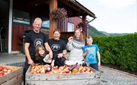 Ein familie nyt haustinga av ferske eple på Spildegarden i Hardanger. Opplev ekte norsk frukttradisjon i hjartet av fjordlandskapet!