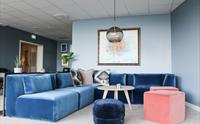 Mjuk sofa i blått med dekorative puter i eit stilfullt loungeområde.