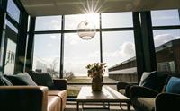Lys og moderne lounge med store vindauge og solstrålar som skin inn.